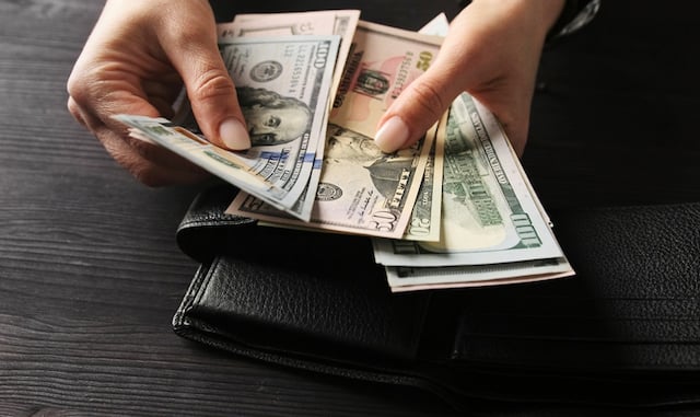 Une femme qui tient une poignée de dollars