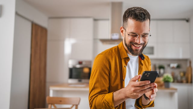 Un homme heureux qui consulte son téléphone portable