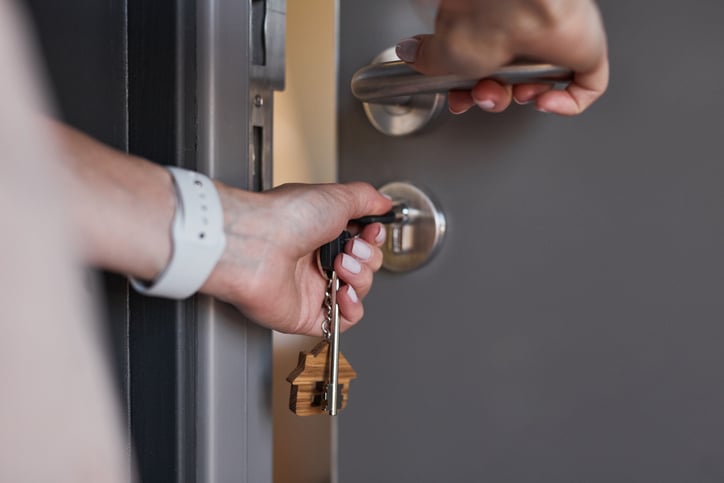 Une femme ouvrant une porte dont elle vient de changer les serrures