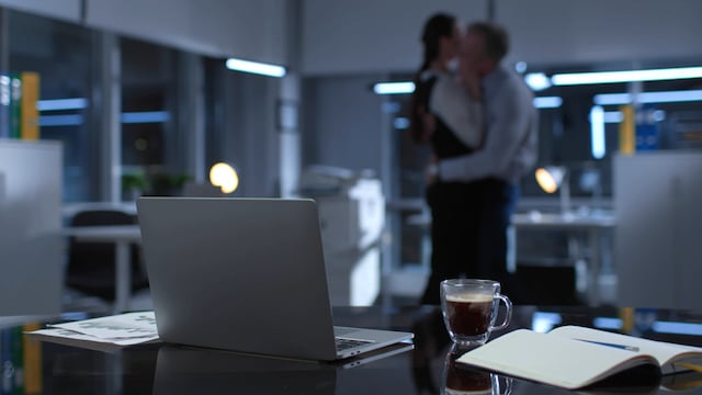 Un homme en train d'embrasser une femme sur son lieu de travail