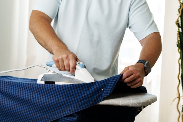 Un homme en train de repasser une chemise