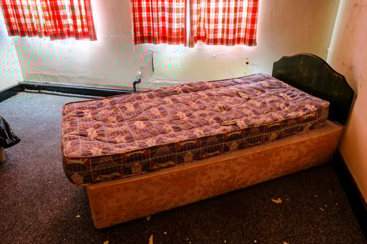 Un lit posé dans une chambre insalubre