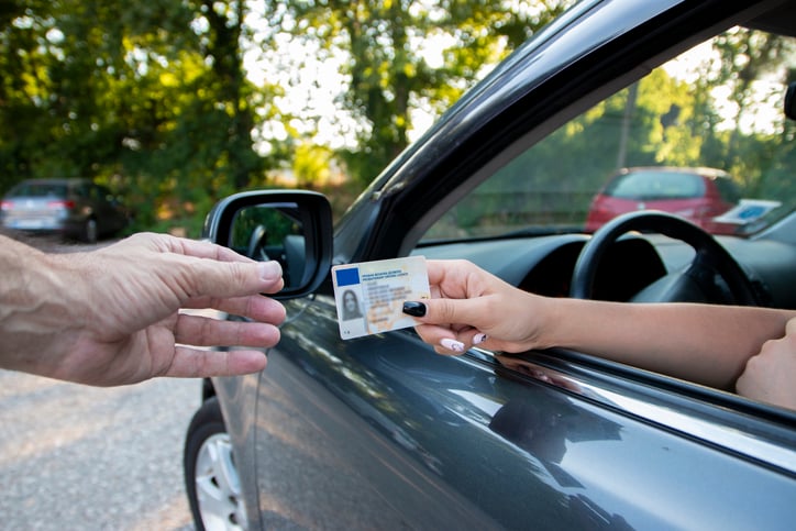 Une femme tend son permis de conduire
