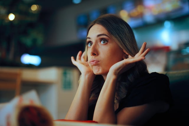 Une femme qui se bouche les oreilles au restaurant