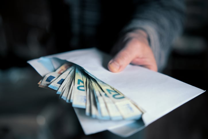 Un homme tient une enveloppe pleine de billets