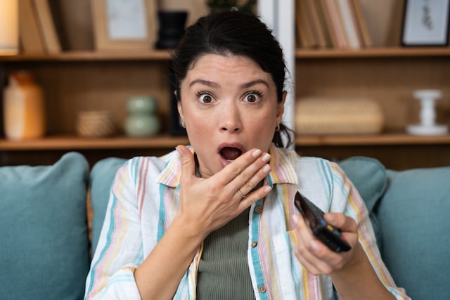 Une femme affichant un air choqu&eacute; devant la t&eacute;l&eacute;vision