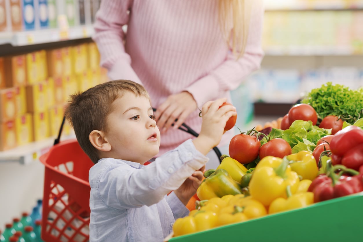 Un enfant prend une tomate dans un supermarch&eacute;