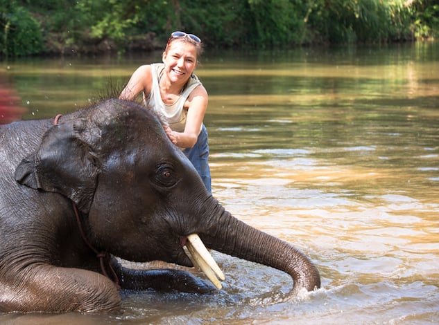 Une touriste en train de caresser un &eacute;l&eacute;phant dans une rivi&egrave;re