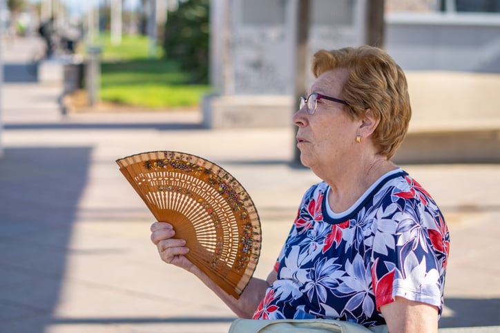 Une femme &acirc;g&eacute;e tient un &eacute;ventail