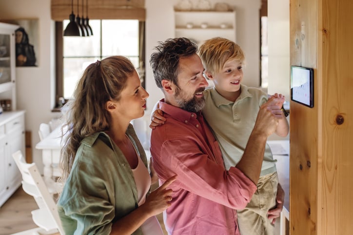 Une famille utilisant son thermostat connect&eacute; 