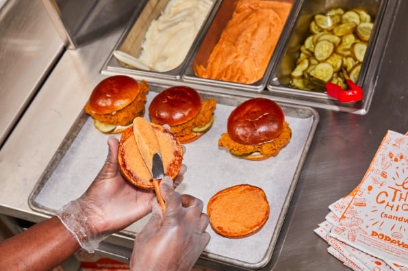 Un employé de chez Popeyes préparant un sandwich
