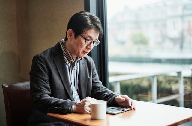 Un Japonais en train de lire son journal dans un café