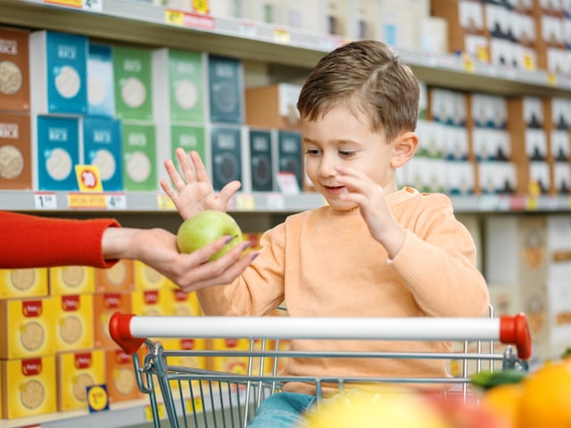 Un petit garçon en train d'attraper une pomme