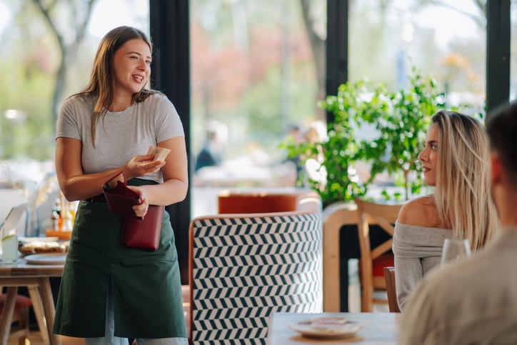 Une serveuse avec des clients