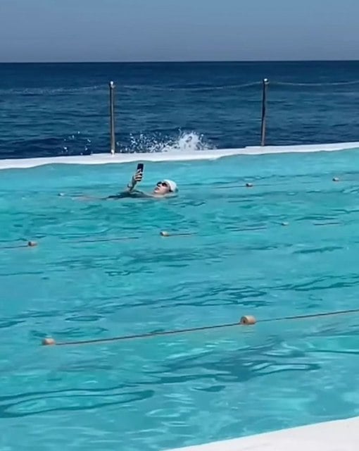Capture d'écran montrant la nageuse utiliser son téléphone portable dans la piscine 