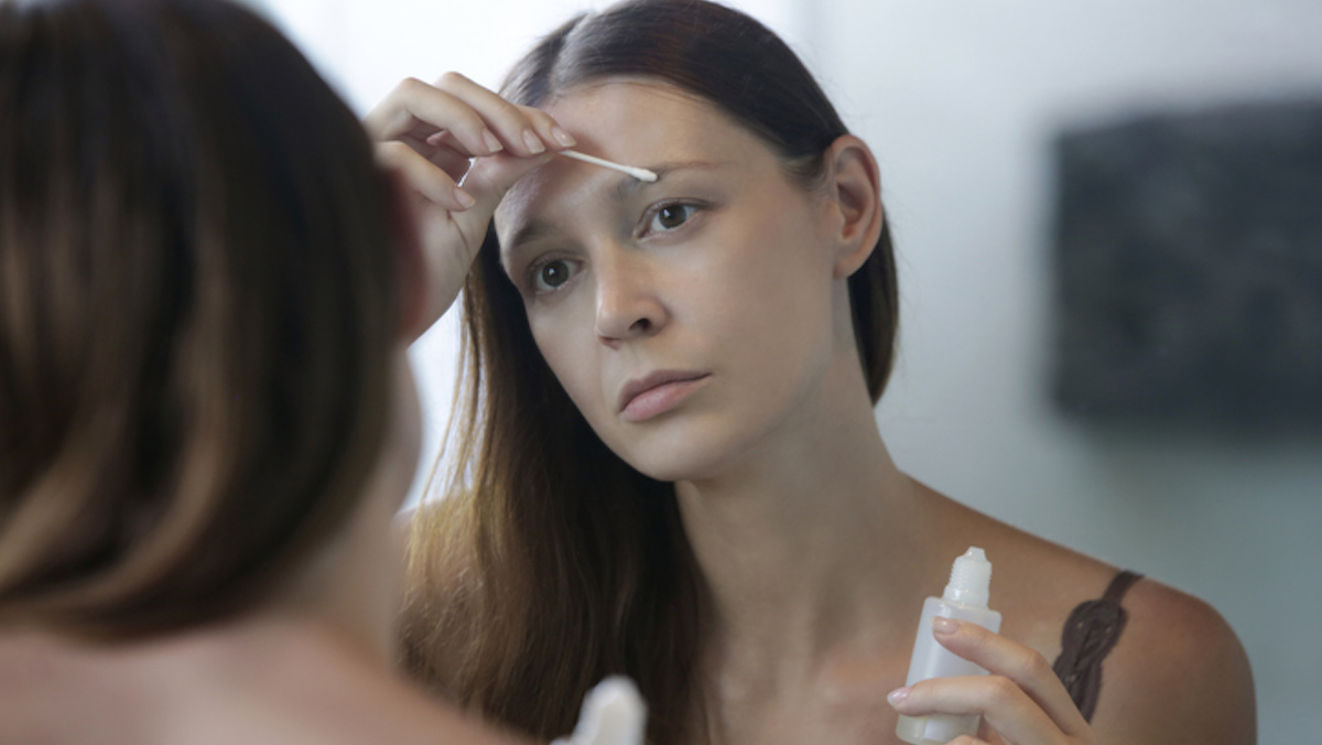 Une femme se passe un s&eacute;rum sur le cil