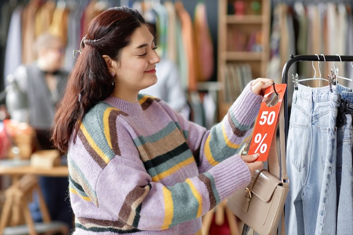 Une jeune femme regardant le prix d'un sac &agrave; main dans une friperie