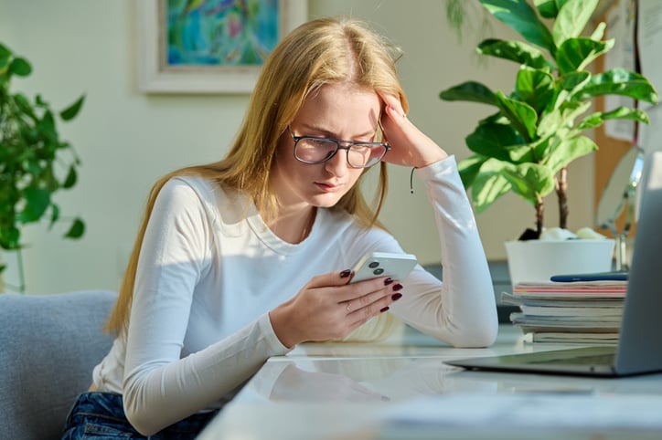 Une jeune femme triste devant son smartphone