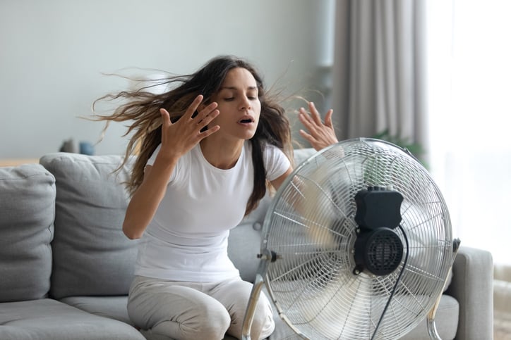 Une femme devant un ventilateur