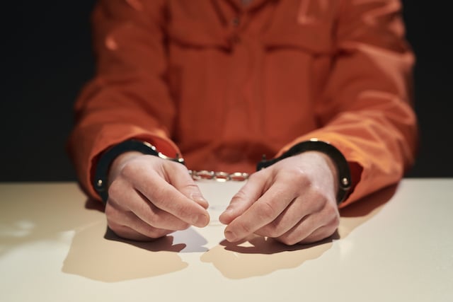 Un prisonnier menott&eacute; portant la tenue orange