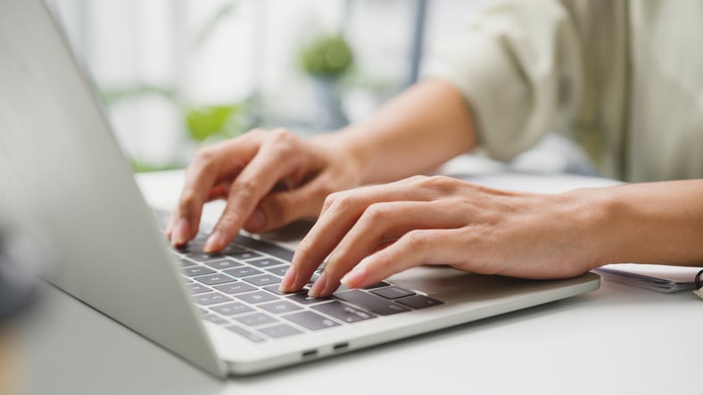 Une femme tape sur un clavier d'ordinateur