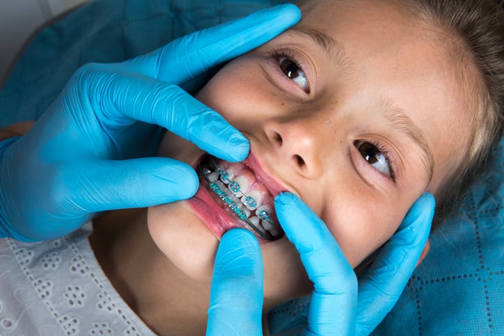 Jeune fille, portant un appareil dentaire, en visite chez le dentiste