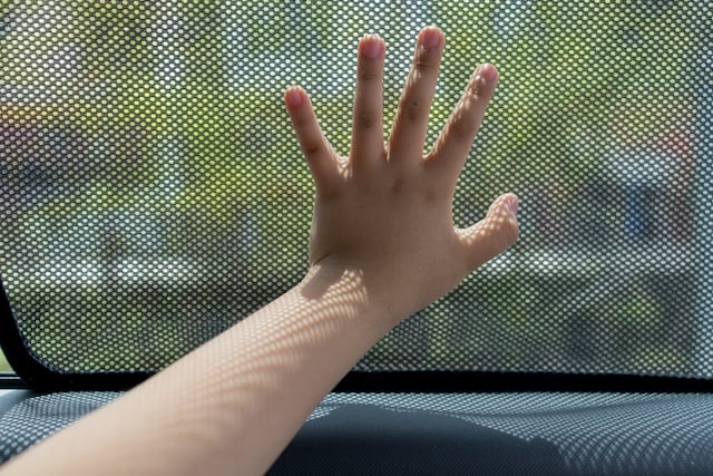 Une main d'enfant sur la vitre d'une voiture