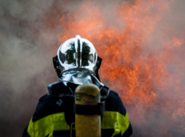 Un pompier se tenant face aux flammes