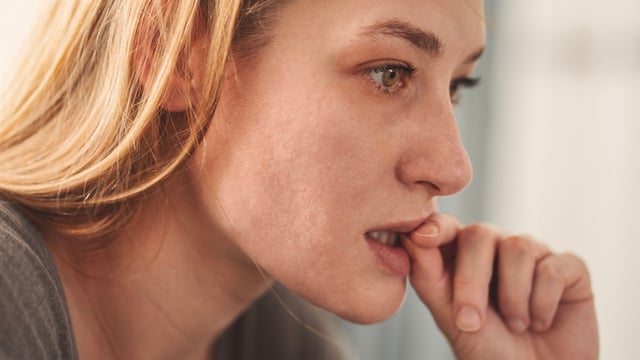 Une femme qui ronge nerveusement les ongles
