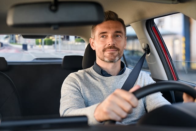 Un conducteur qui sourit en regardant son r&eacute;troviseur 