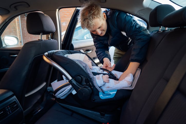 Un homme attache un b&eacute;b&eacute; dans un si&egrave;ge auto
