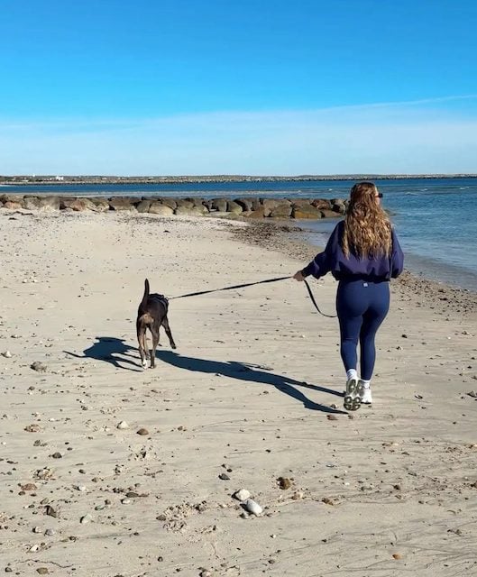 Kaitlyn Ballard en train de promener un chien sur la plage 