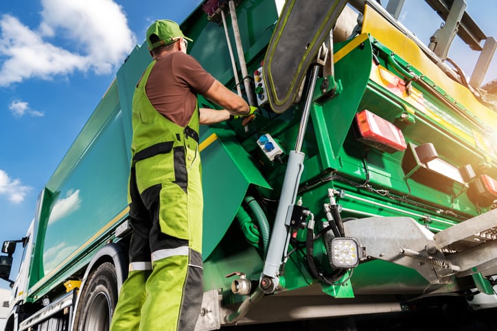 Un &eacute;boueur en action devant un camion poubelle