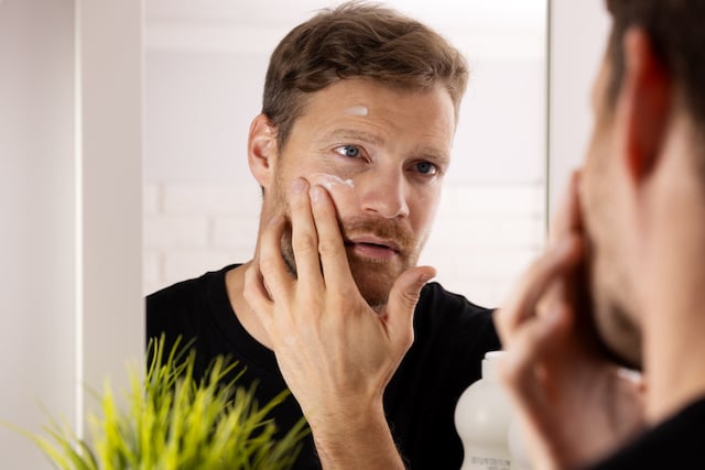 Un homme qui &eacute;tale de la cr&egrave;me sur son visage