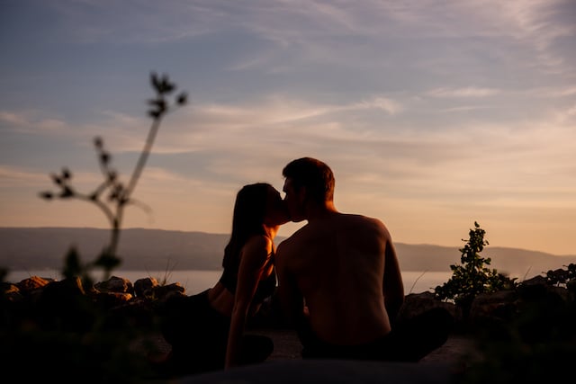 Un couple en train de s'embrasser devant un coucher de soleil