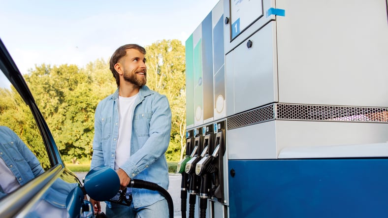 Un automobiliste fait un plein d'essence, tout sourire
