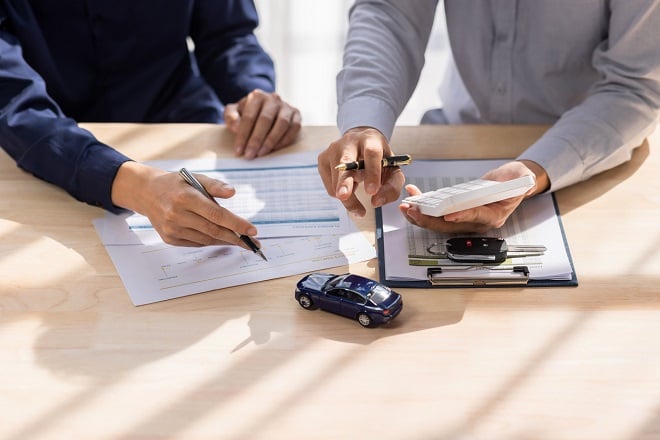 Concessionnaire faisant signer un document à un acheteur