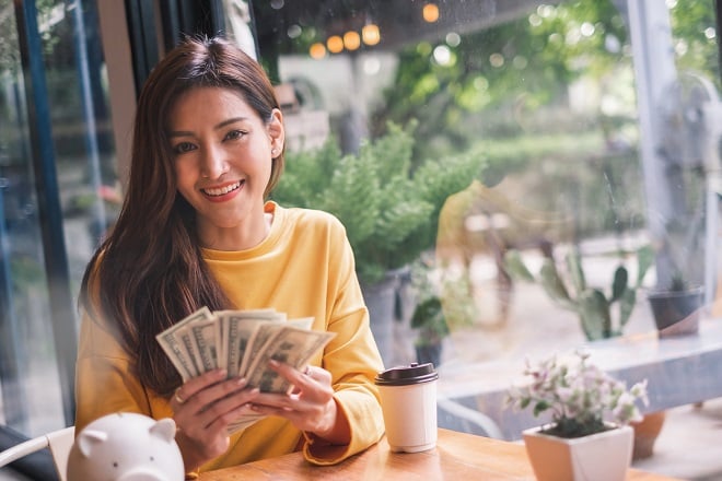 Jeune femme tenant une liasse de billets en dollars
