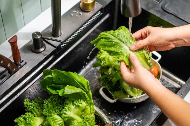 une personne qui lave des feuilles de salade