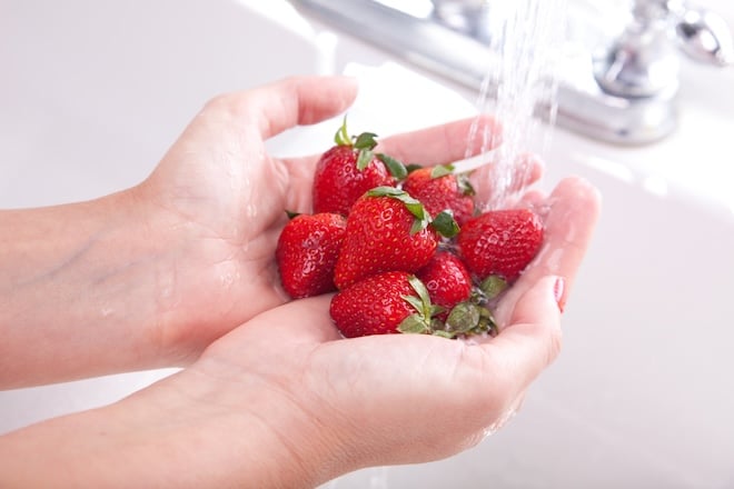 une personne qui nettoie des fraises sous l'eau