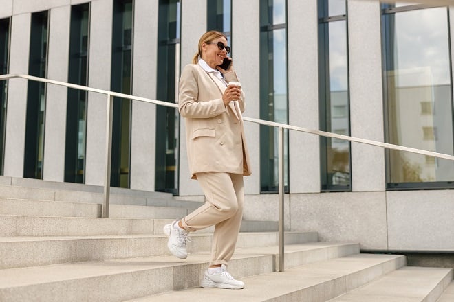 Femme d'affaires au téléphone marchant avec un café à la main