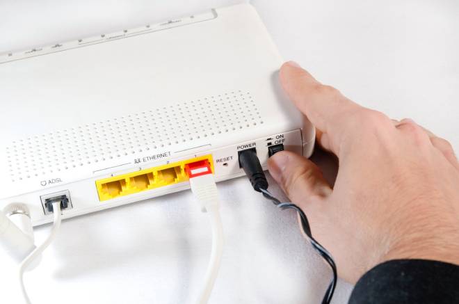 Une main &eacute;teignant un bouton sur une box internet