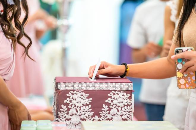 Invit&eacute;e de mariage mettant une enveloppe dans une urne