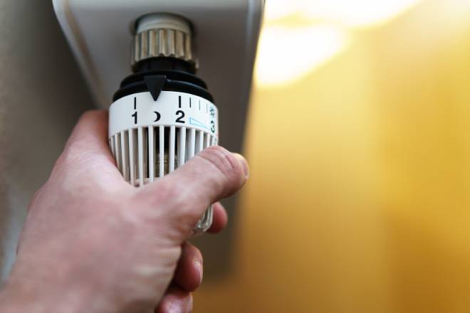 Homme ajustant le thermostat d'un radiateur