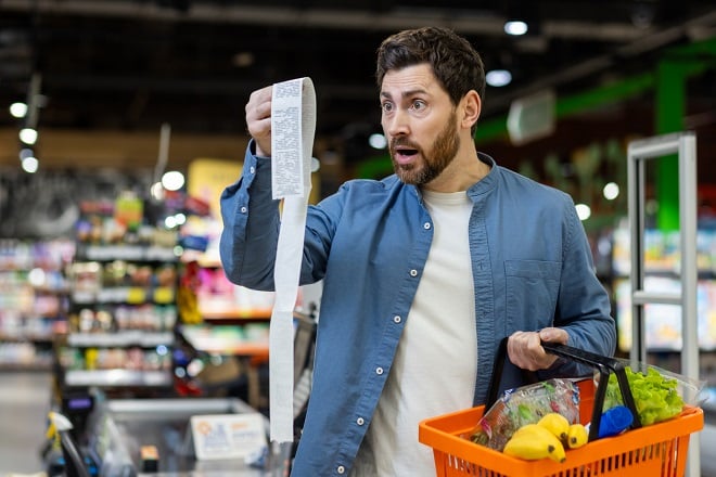 Homme étonné en regardant son ticket de caisse au supermarché