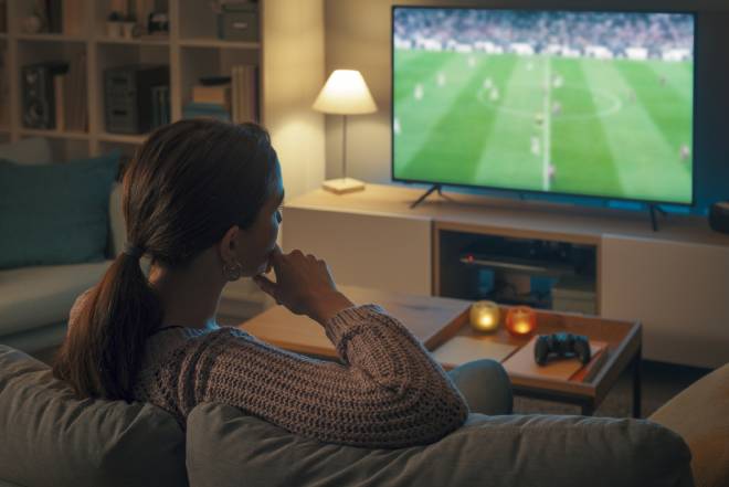 Jeune femme regardant un match de foot &agrave; la t&eacute;l&eacute;