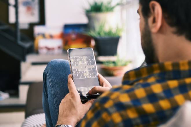 Jeune homme jouant au Sudoku sur son smartphone