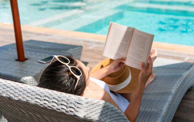 Jeune femme lisant sur un transat au bord de la piscine