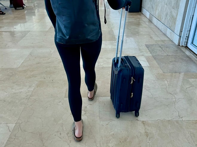 Passagère portant un legging et poussant sa valise à l'aéroport
