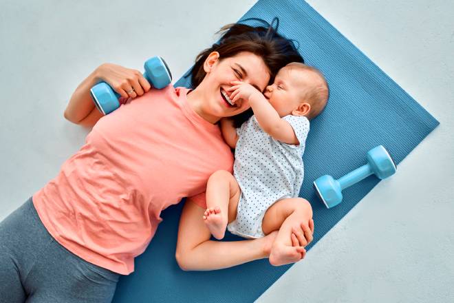 Une maman et son b&eacute;b&eacute; sur un tapis de sport et avec des halt&egrave;res